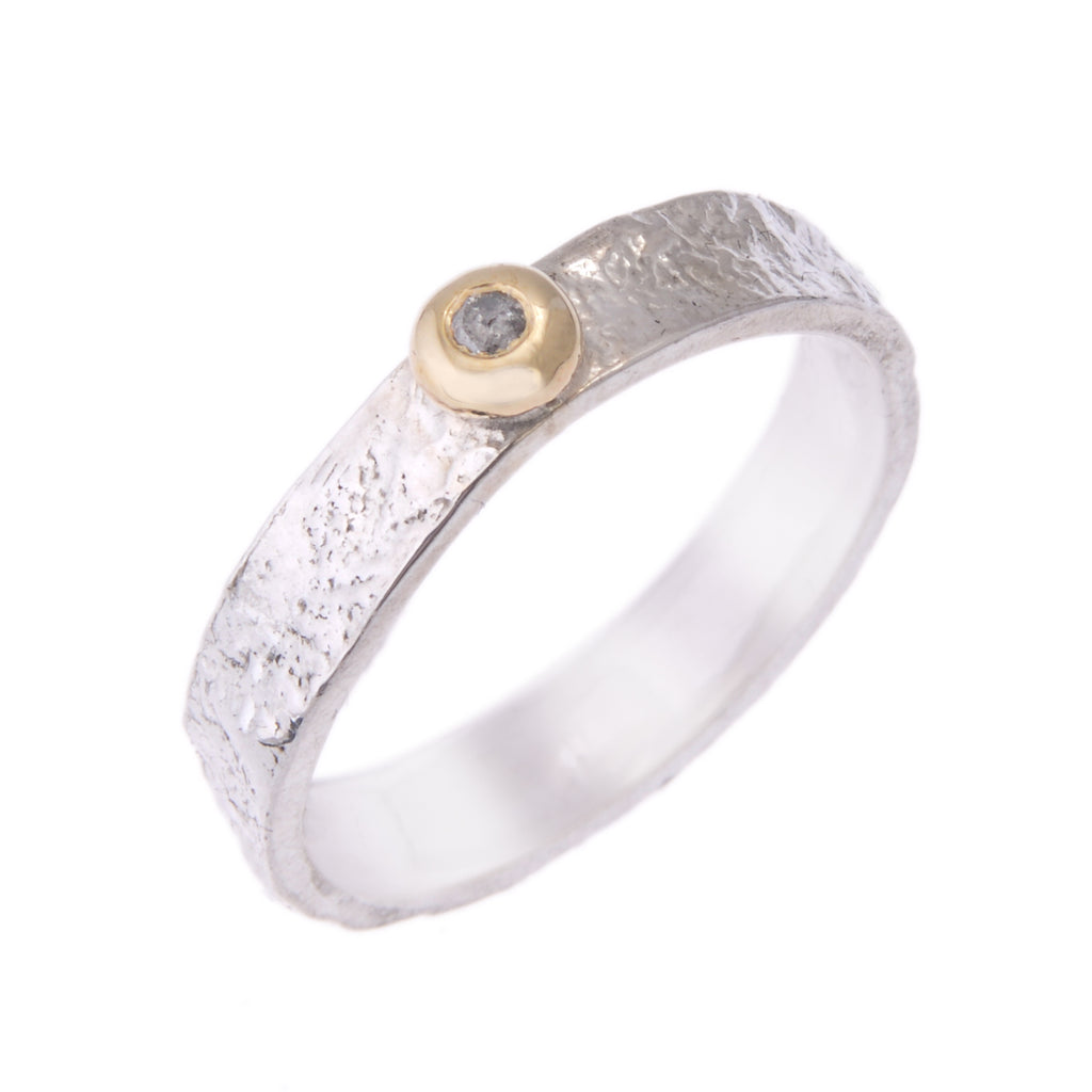 5mm wide silver ring standing on end. The outside of the ring is textured like bark. There is a pale yellow bud of gold on the top of the ring with a grey diamond set within it