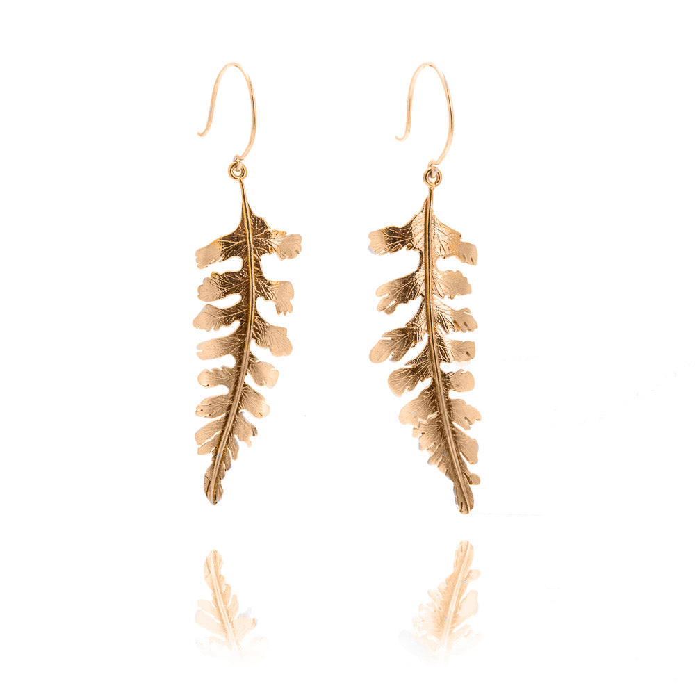 A pair of gold fern shaped earrings hanging from gold hook wires