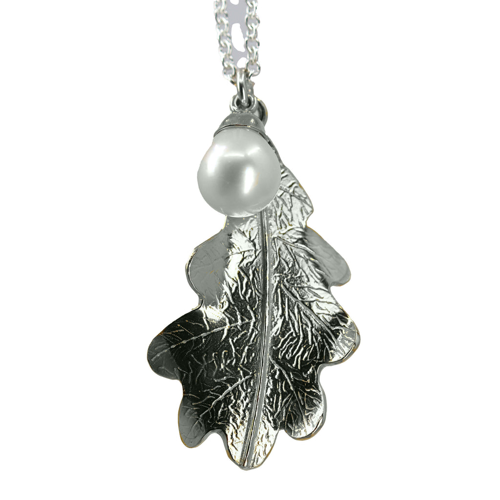 A large shiny silver oak leaf pendant and white teardrop pearl hanging from a silver linked chain