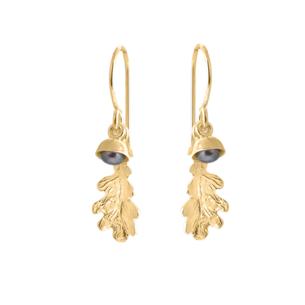 Gold hook earrings with a small oak leaf charm and a tiny black pearl in an acorn cup charm