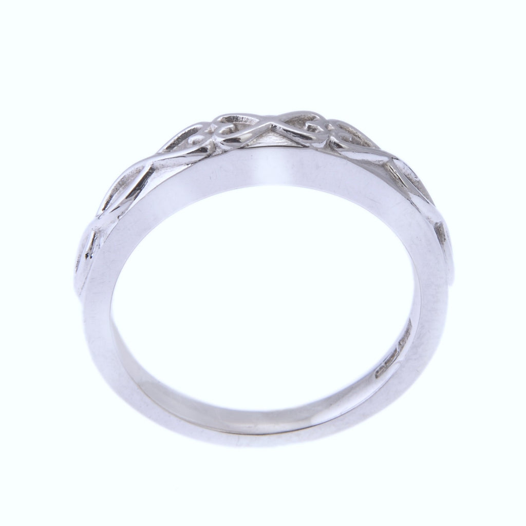 Side view of a silver coloured ring. There is a heart design on the front of the ring that stands proud of the surface.
