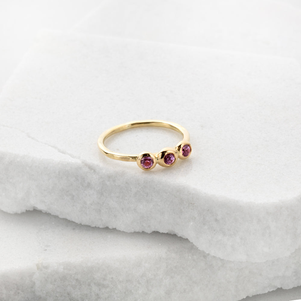 Slim gold engagement ring with 3 pink sapphires
