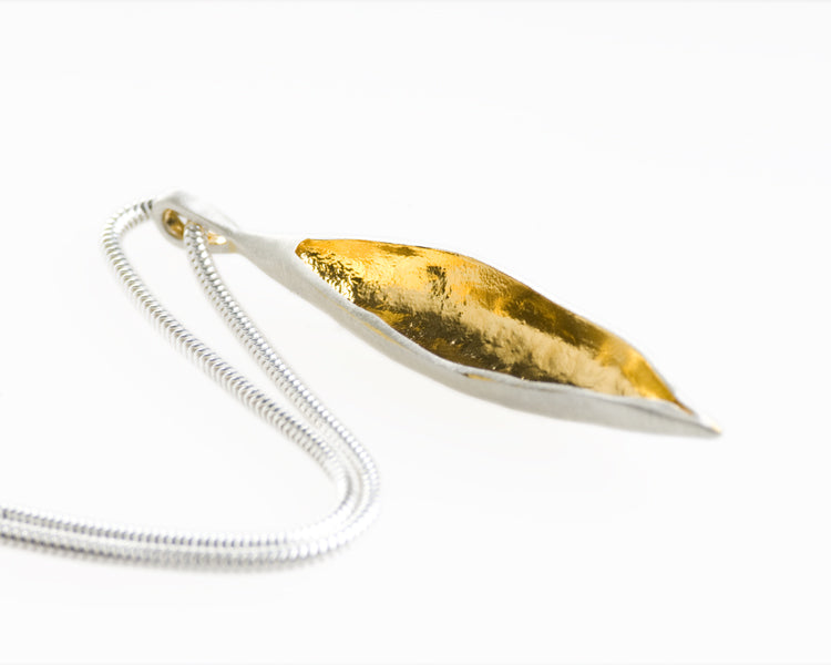 big silver pod pendant with gold inside