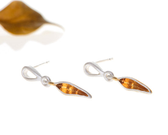 leaf shape earrings in silver and gold laying on side