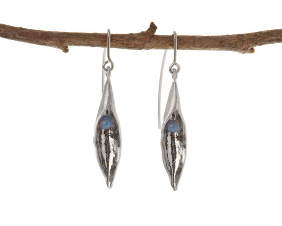 Medium silver pea pod hook earrings with black pearls inside, hanging from a branch
