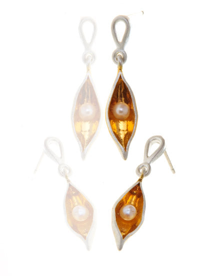 Small silver and gold pods with an off white pearl inside, hanging from a small silver stud earring