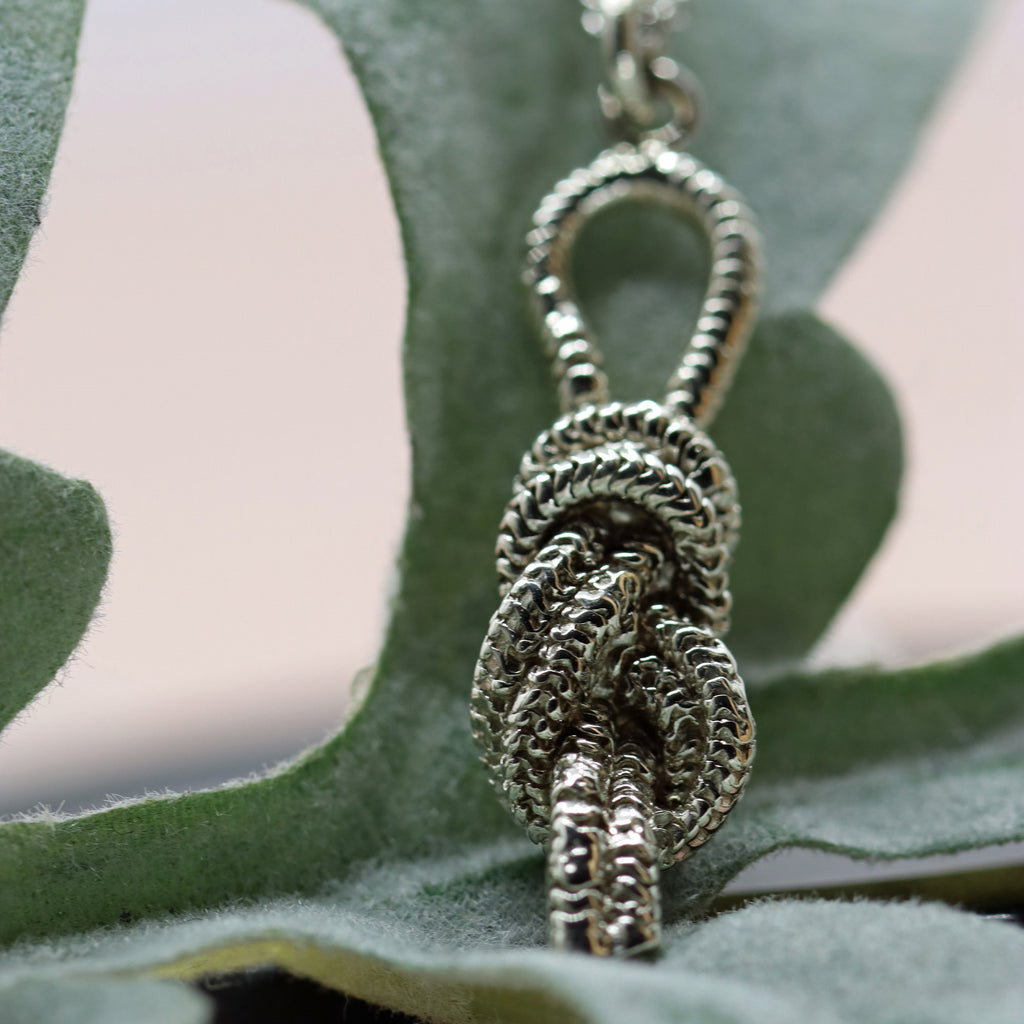 a white gold pendant in the shape of a knot made from rope
