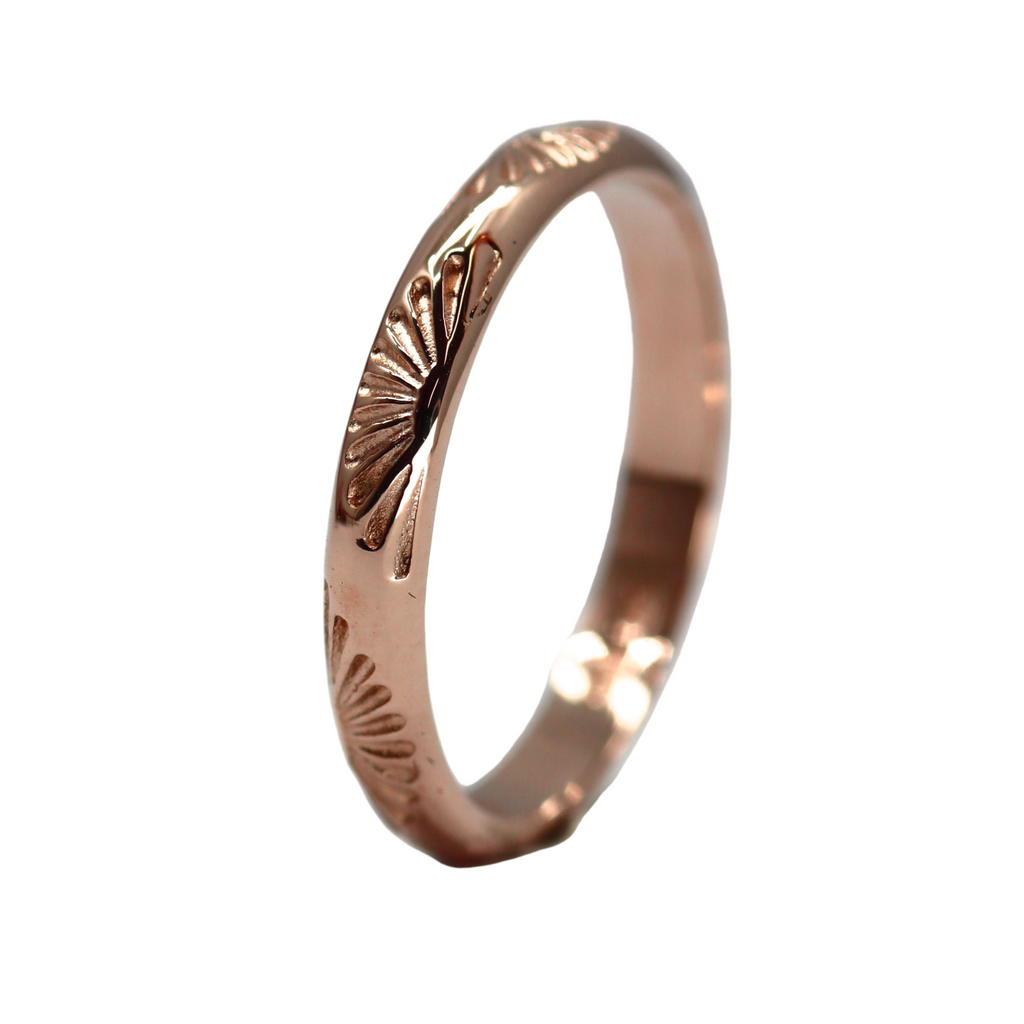 Rose gold ring with sunset design on a white background