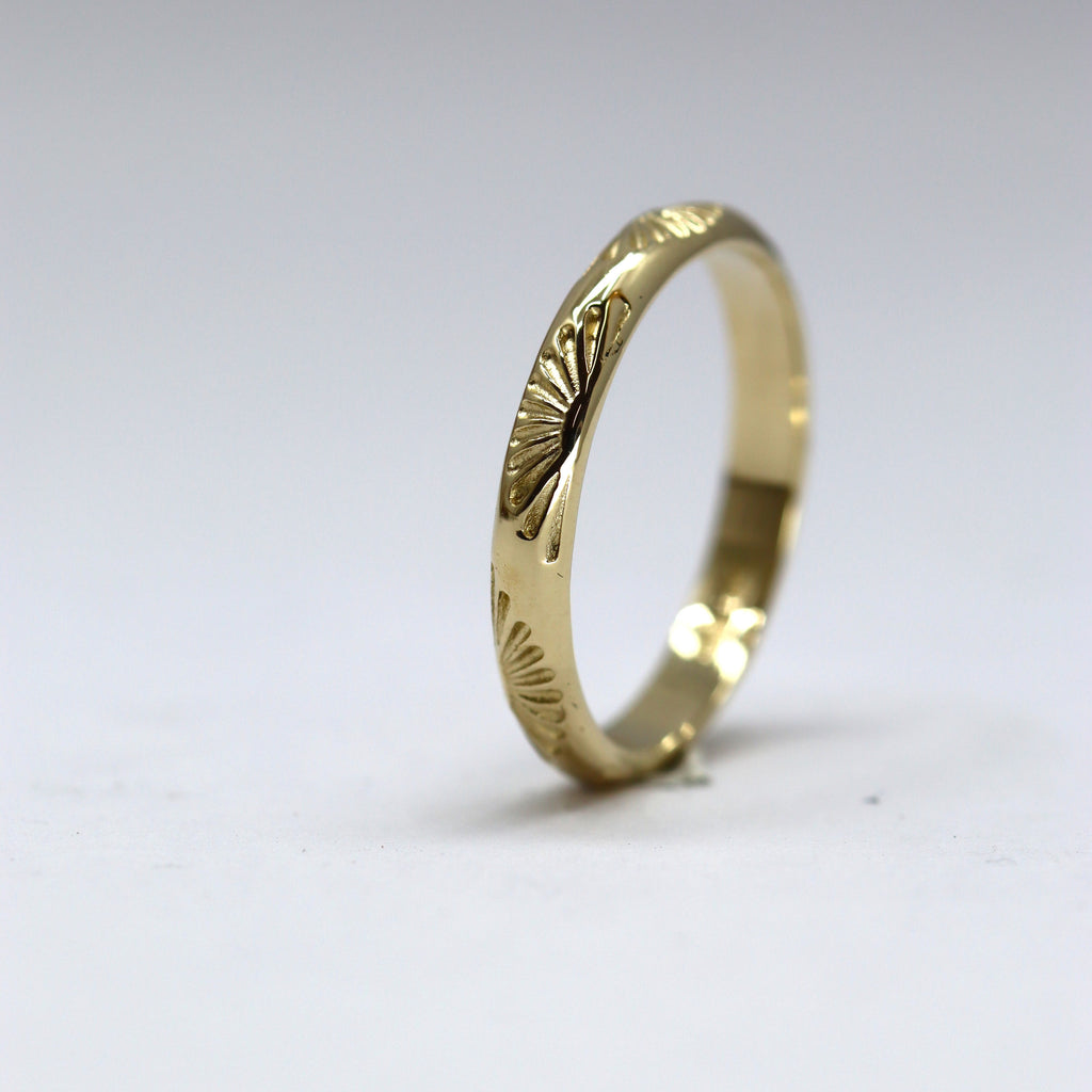 Gold ring with intricate design on a light gray background