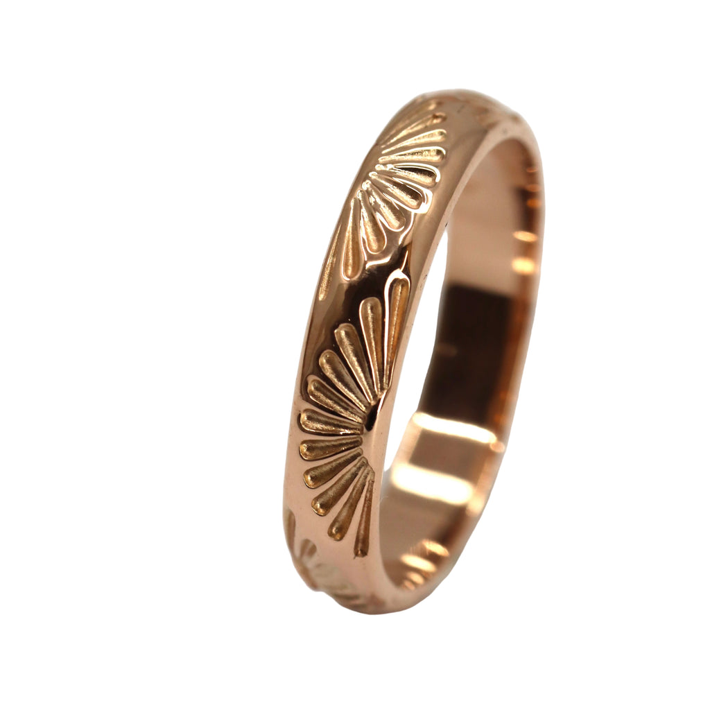 Rose gold ring with sunrise pattern on a white background