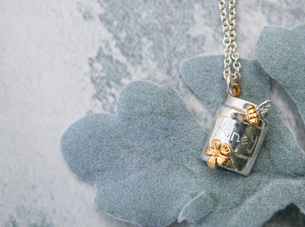 Silver honey jar necklace with gold plated bee and flower and the word honey etched on the jar