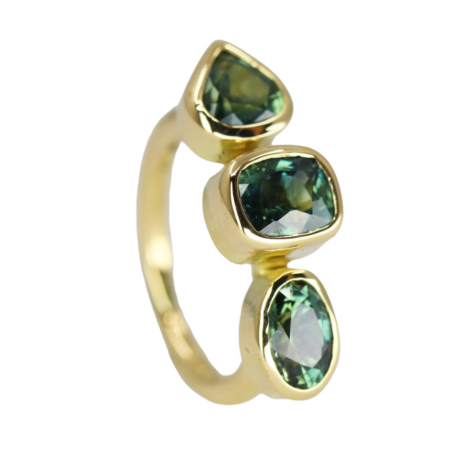 Yellow gold ring standing on end with 3 large green sapphires