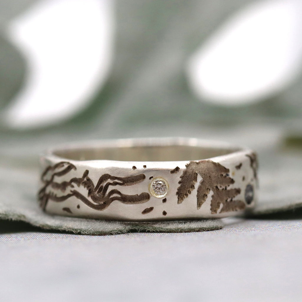 Silver ring with engraved design on a neutral background