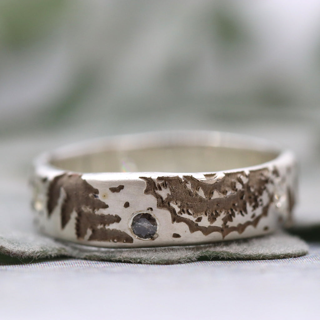 Silver ring with engraved ammonite pattern on a blurred background