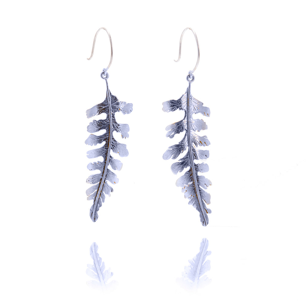 A pair of large fern shaped earrings hanging from silver hook wires