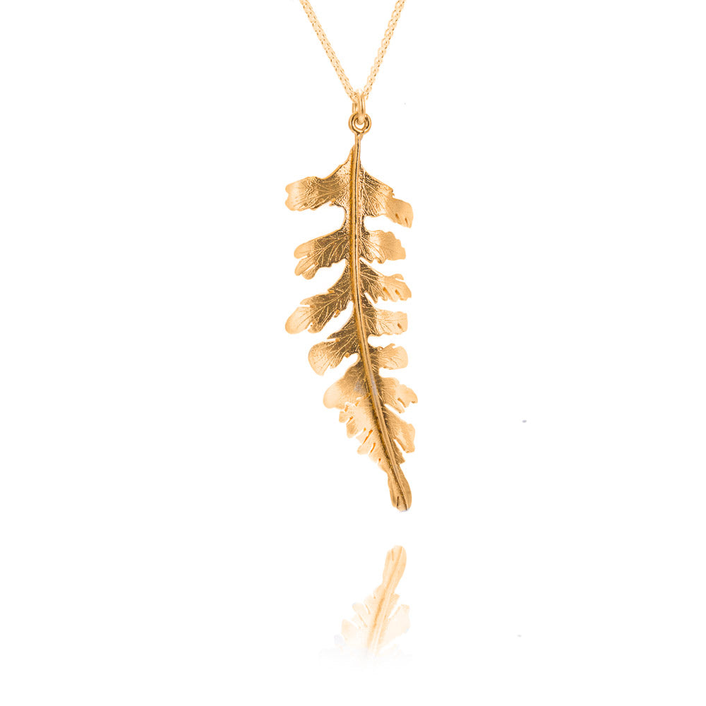 A large gold fern pendant on a gold chain