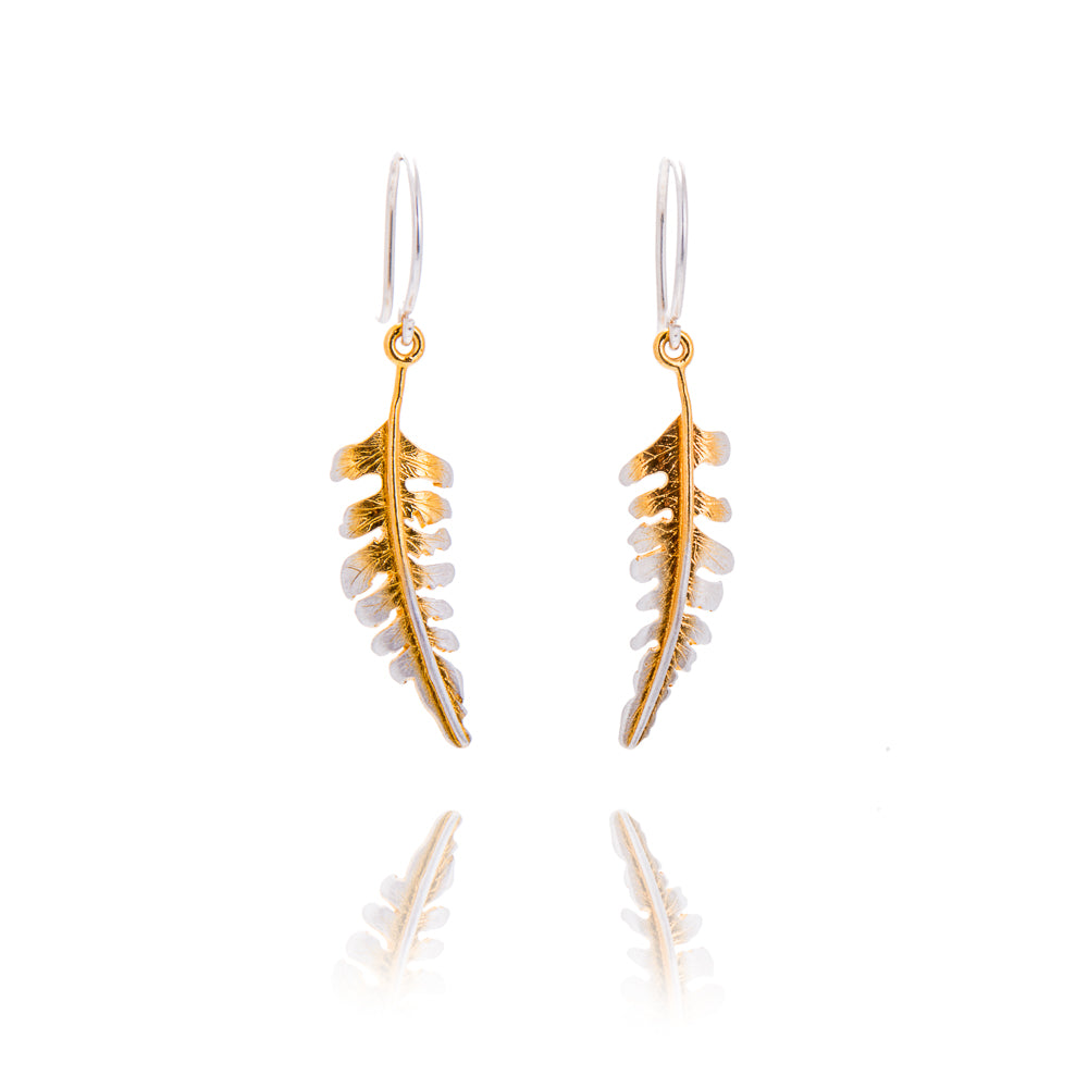 A pair of small fern shaped earrings on silver hook wires. The ferns are curved towards each other. They have gold down the centre with silver edges