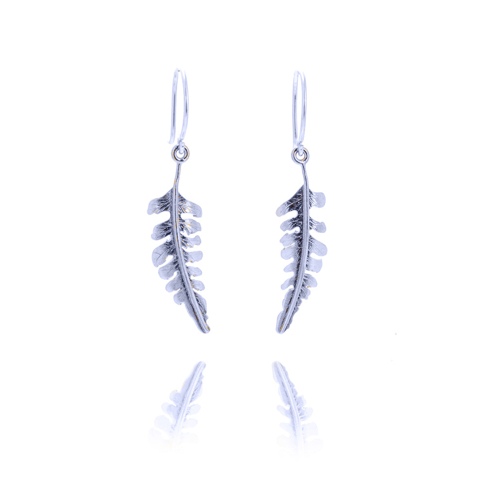 Small fern shaped earrings hanging from silver hook fittings