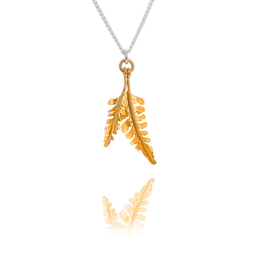A tiny and a small fern shaped pendant in gold on a silver chain