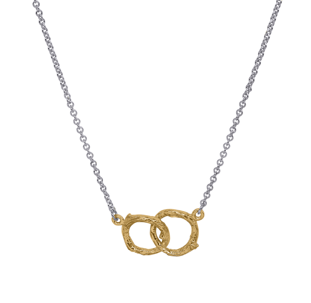 Two gold twig textured interlinked circles hang from a silver necklace