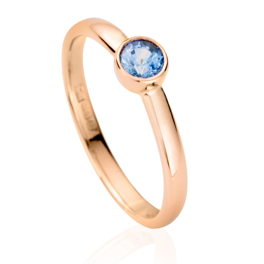 Rose gold engagement ring with pale blue sapphire in rubover bezel