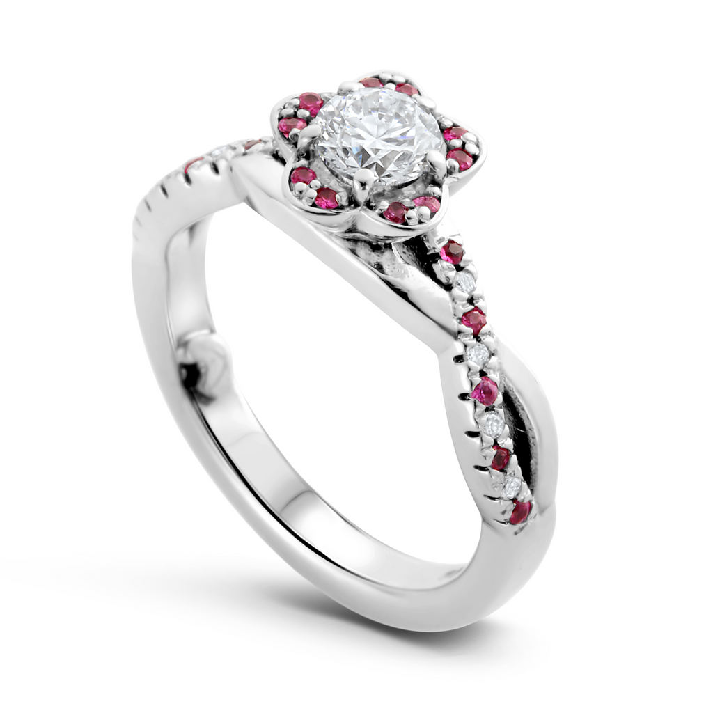 white gold flower shaped engagement ring with white diamond surrounded by pink sapphires in the petals and down the shoulders