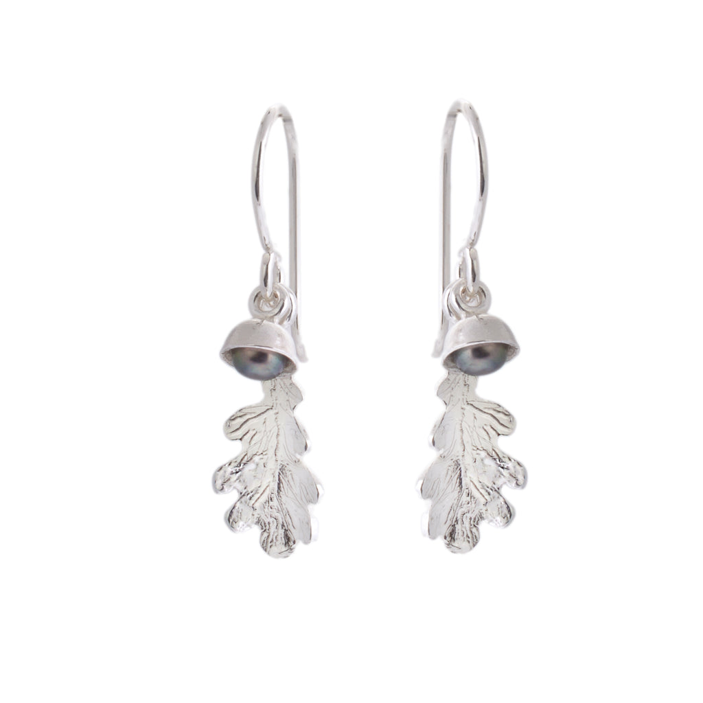 Silver hook earrings with a tiny acorn leaf and a black pearl in a tiny cup charm hanging from each