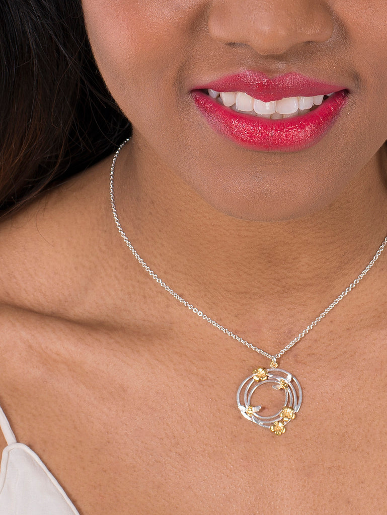 Woman wearing round necklace with bee and flowers