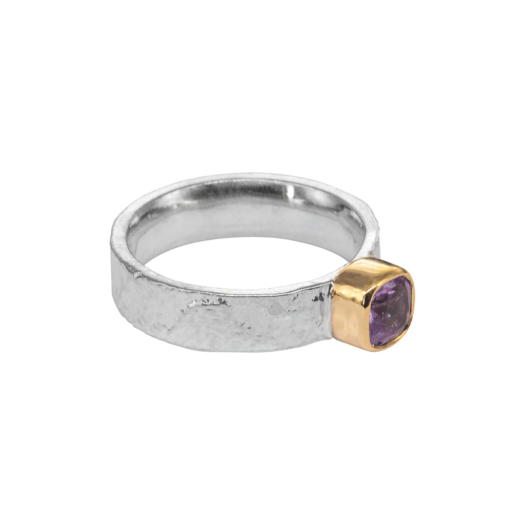 silver textured ring on its side with amethyst in high gold setting
