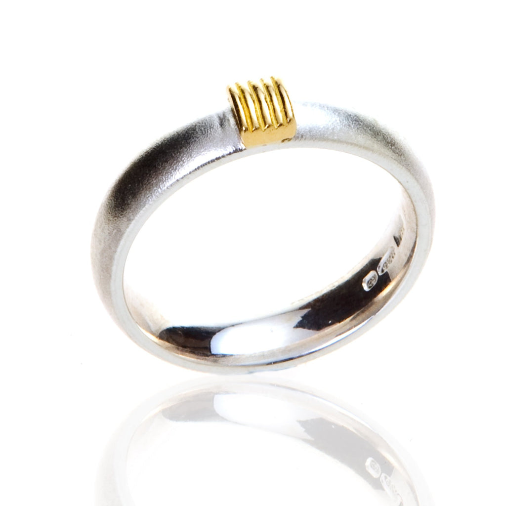 Silver ring standing on end with 5 gold wires on the top