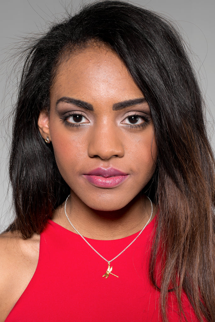 Black woman wearing a gold dragonfly necklace