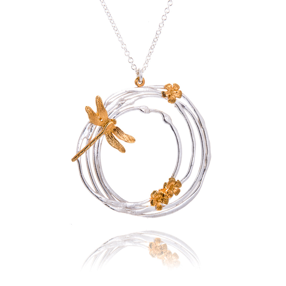 large circular silver pendant with gold dragonfly and flowers
