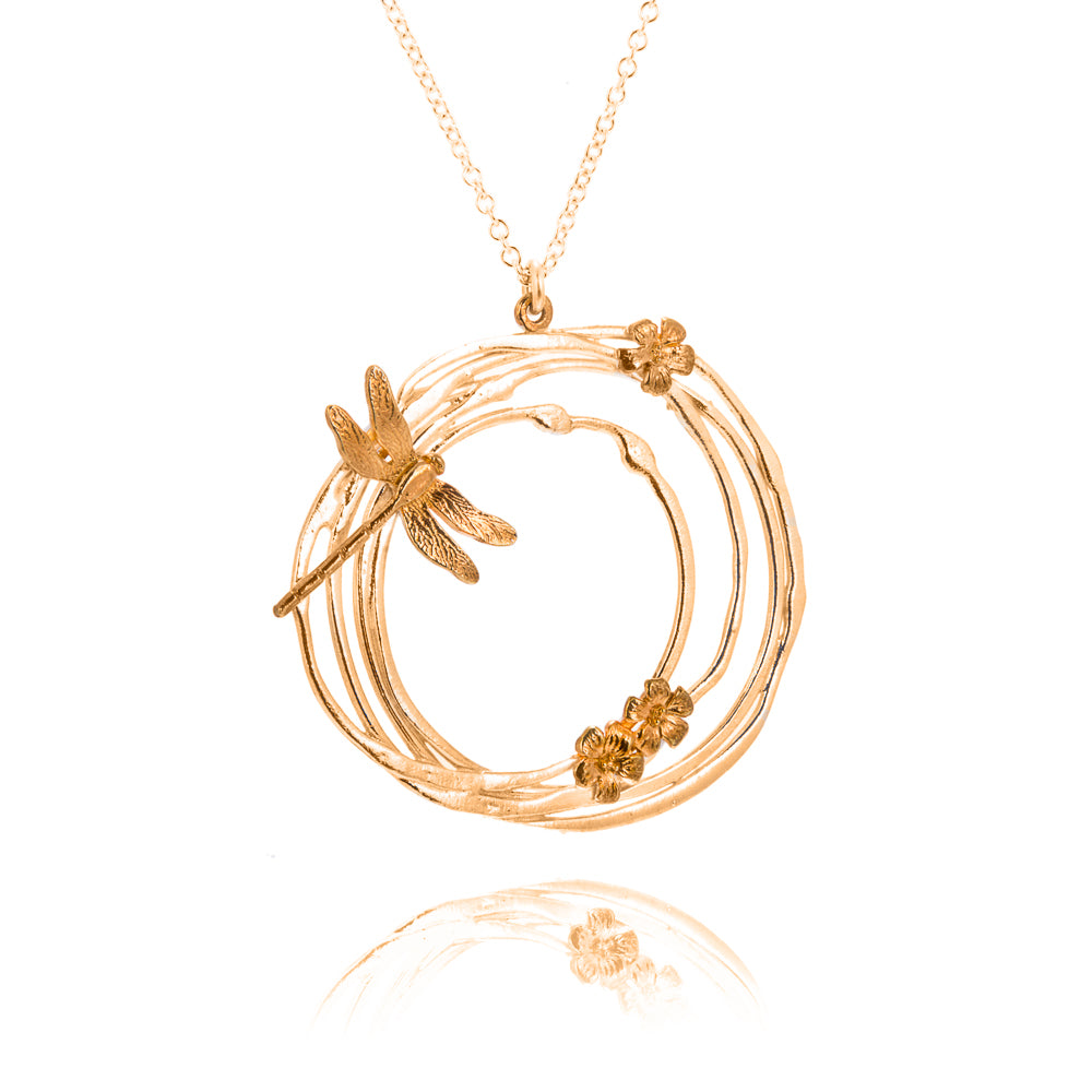 large gold circular pendant with dragonfly and flowers