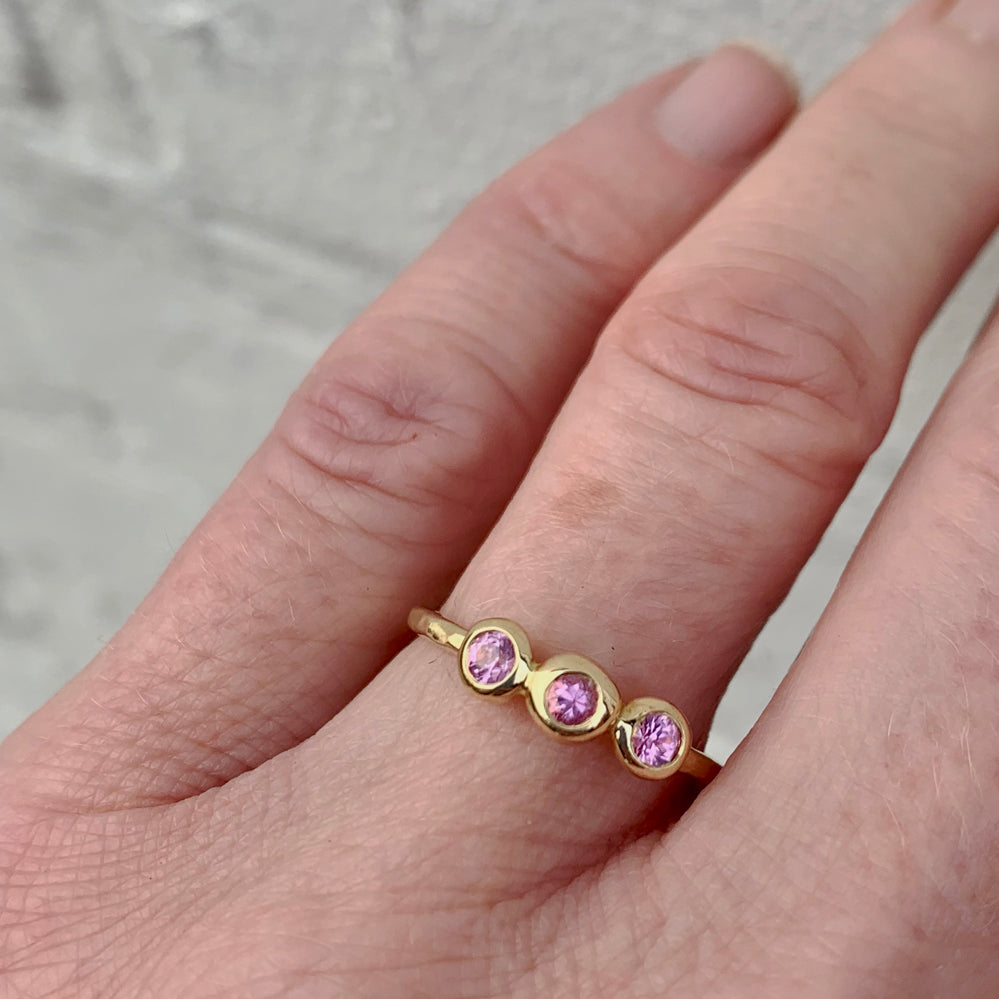 slim hammered gold ring with 3 pink sapphires on finger