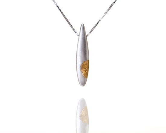 Teardrop silver pendant with gold sun pattern to one side, on silver chain