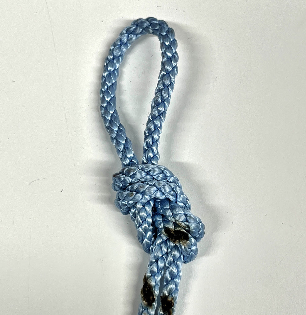 a blue rope tied into a knot used in indoor rock climbing