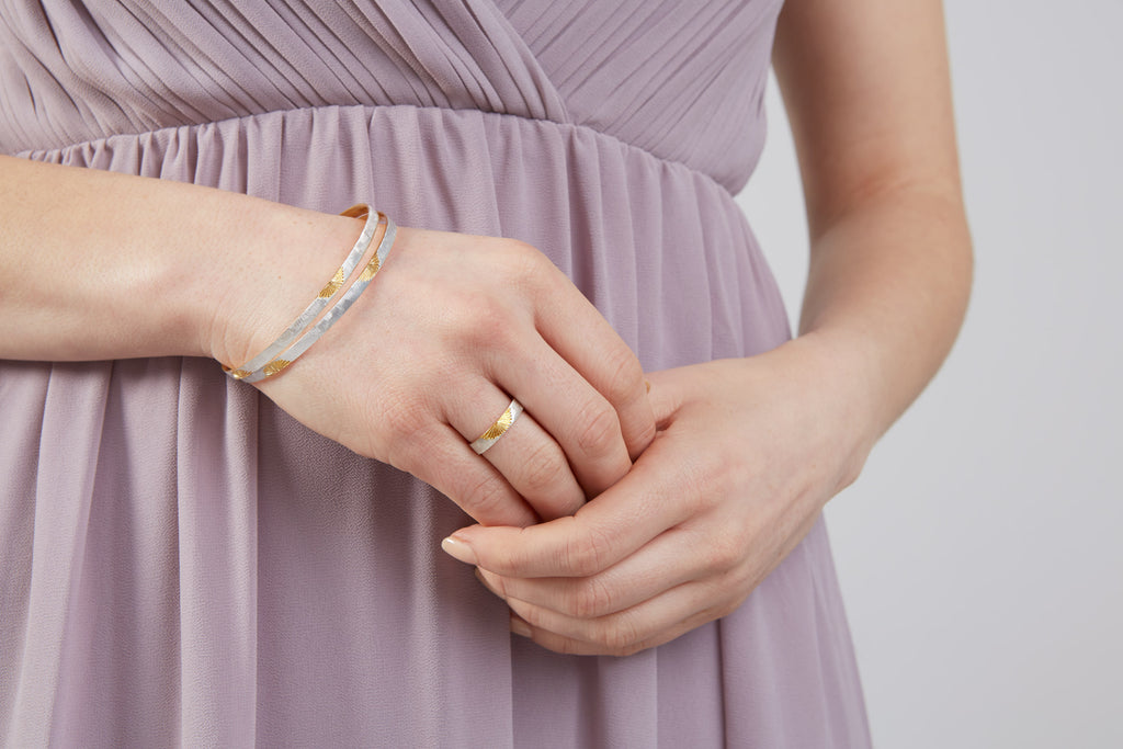 woman wearing silver bangles and a silver ring with sun engravings